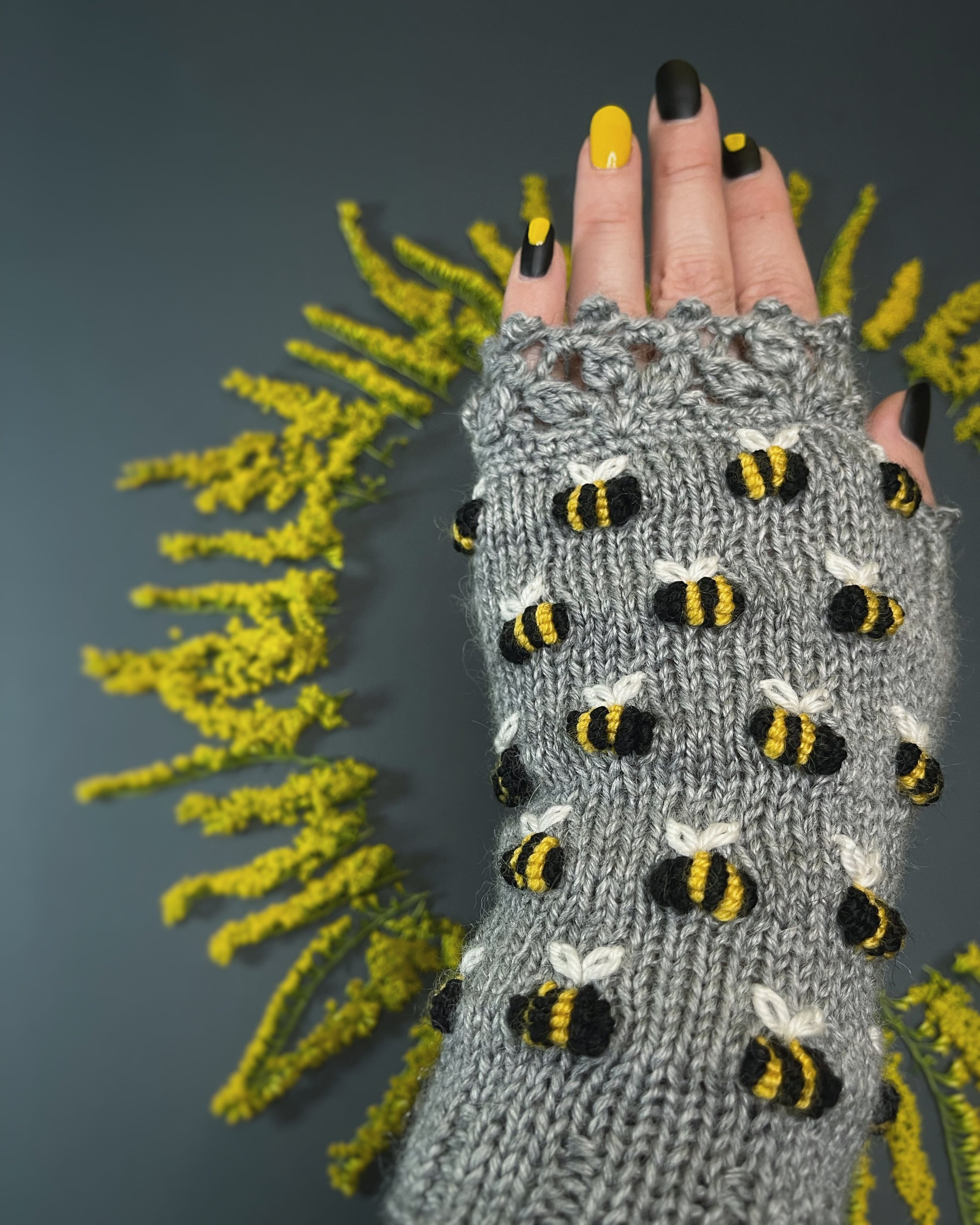 Gray hand knitted gloves with embroidered bees