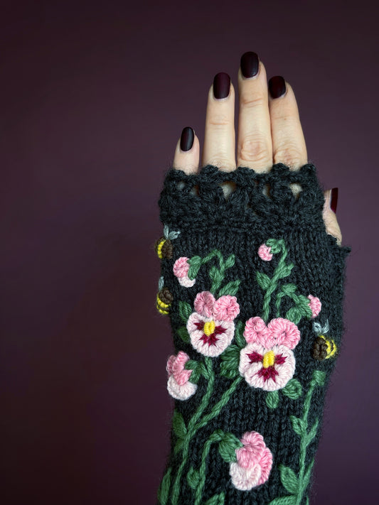 Pink embroidered pansy flowers with bees on the gray gloves